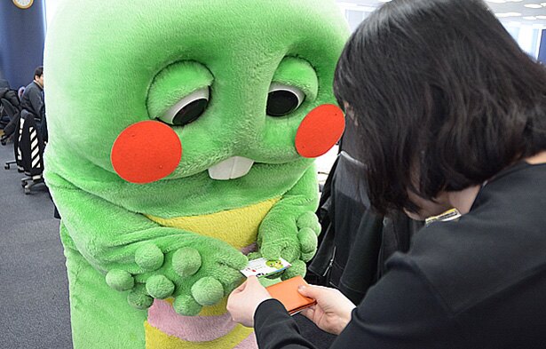 熊本県スポーツ応援特命大使に任命されたガチャピン。「赤ほっぺ」を付けて「くまチャピン」の名刺を差し出す。